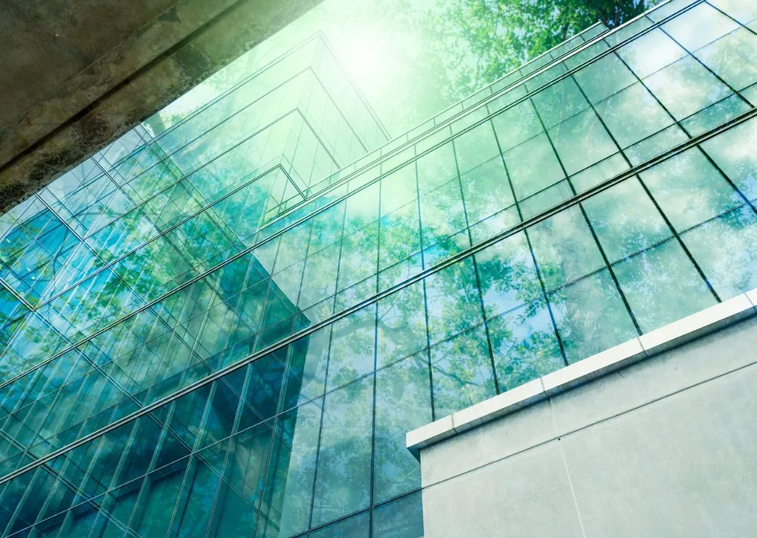 Glass building reflecting trees and sky
